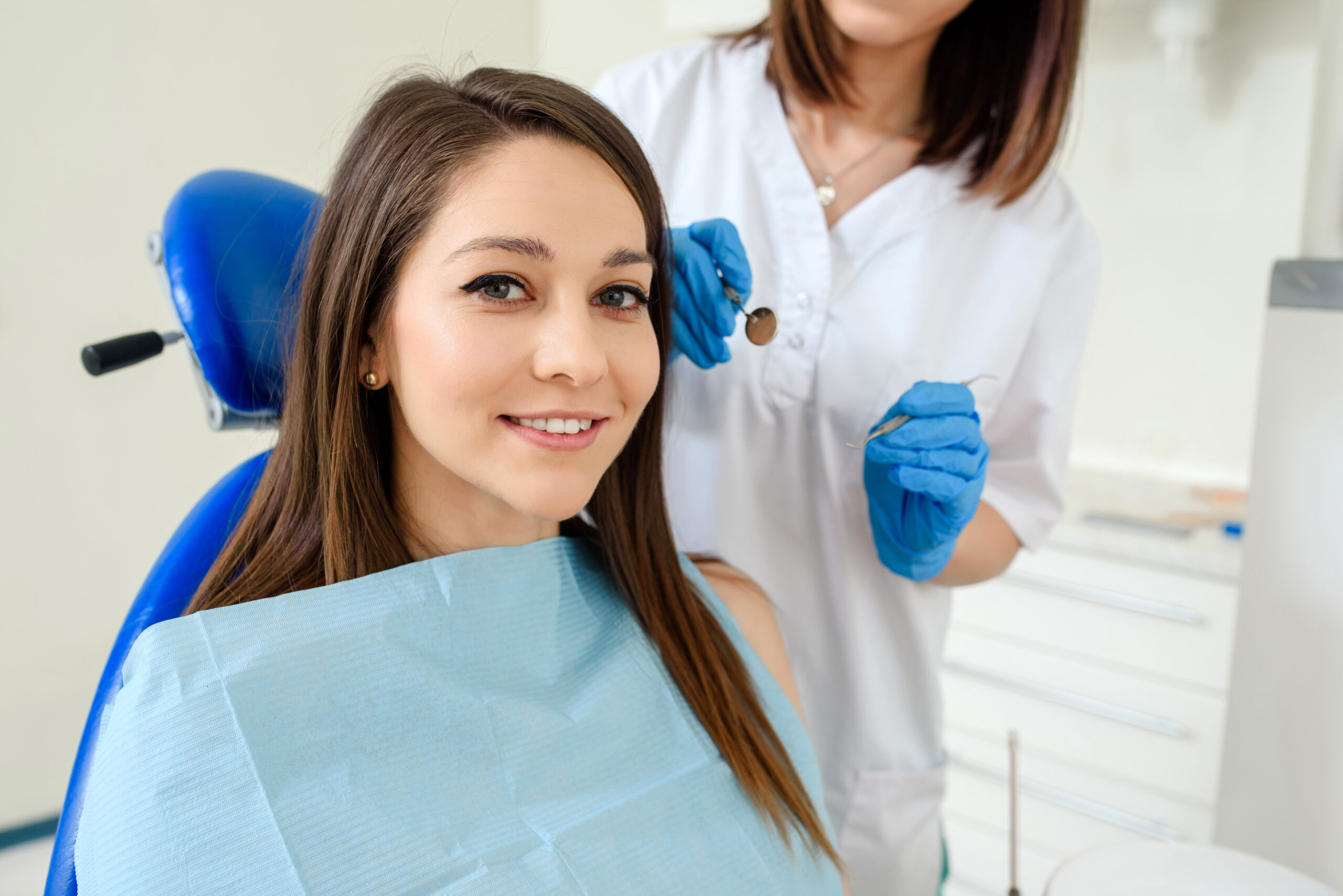 Young happy smiling woman patient in a dental clinic is receiving a dental treatment