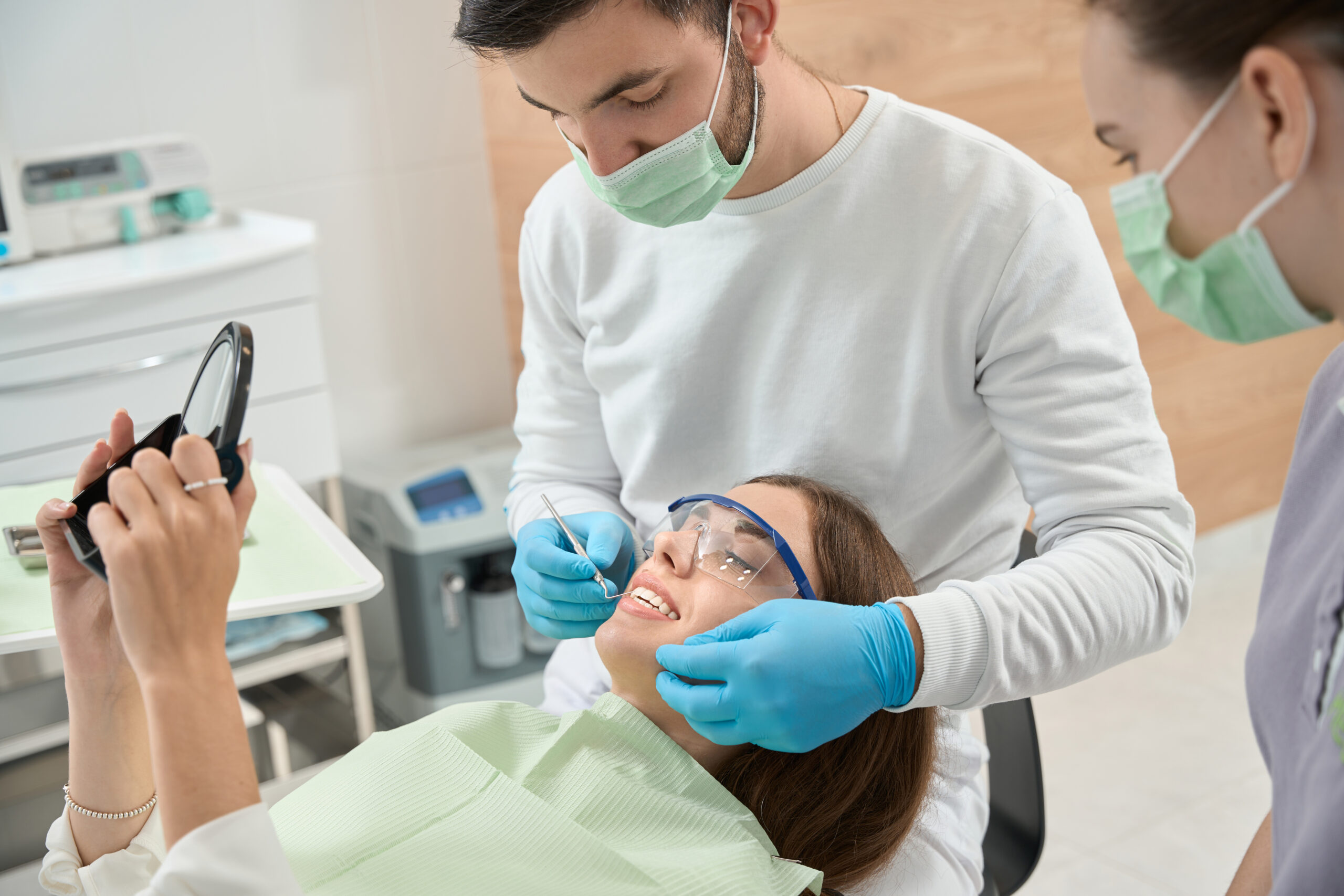 Stomatologist conducting thorough examination of young female patient